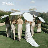 Bridesmaids holding paper umbrella at the sunny summer wedding party
